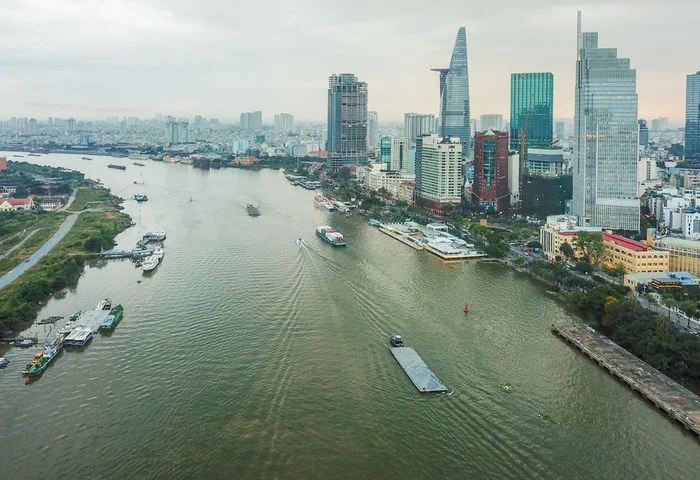 Ảnh thành phố bên sông với tàu thuyền và dãy nhà cao tầng ven bờ