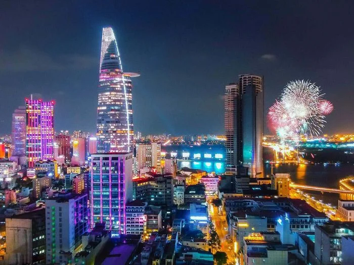 Ảnh thành phố về đêm rực rỡ với tòa nhà chọc trời và pháo hoa bên sông